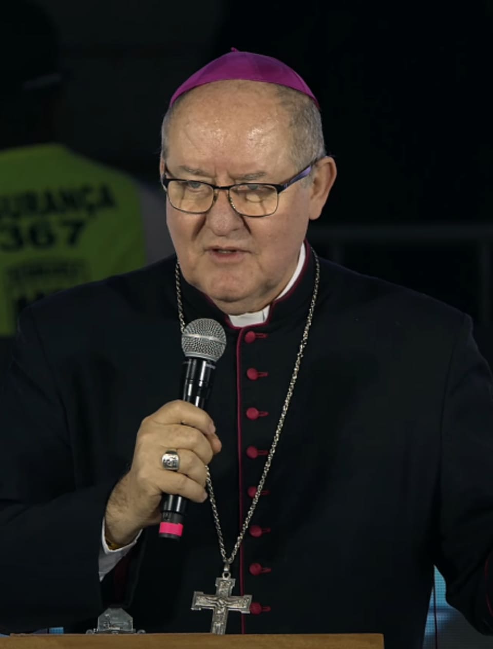 Dom Adair pregando, com o microfone na mão